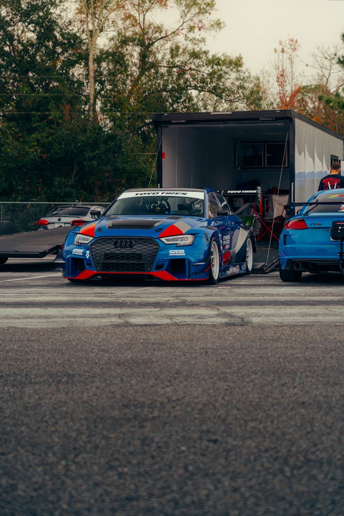 Vibrant blue and red race cars on an outdoor track, ready for a race.