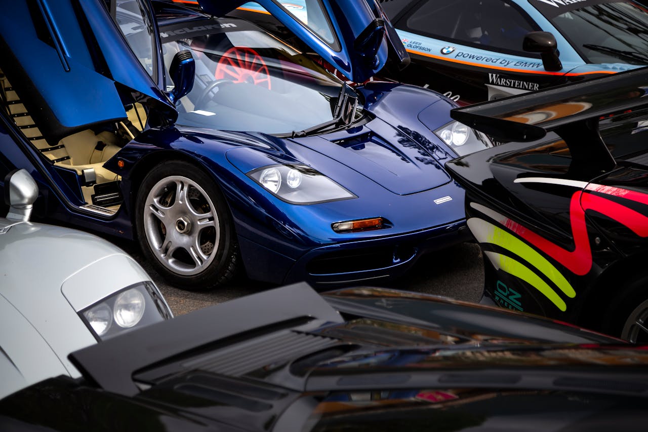 A collection of rare and iconic sports cars displayed with open doors showcasing their design.