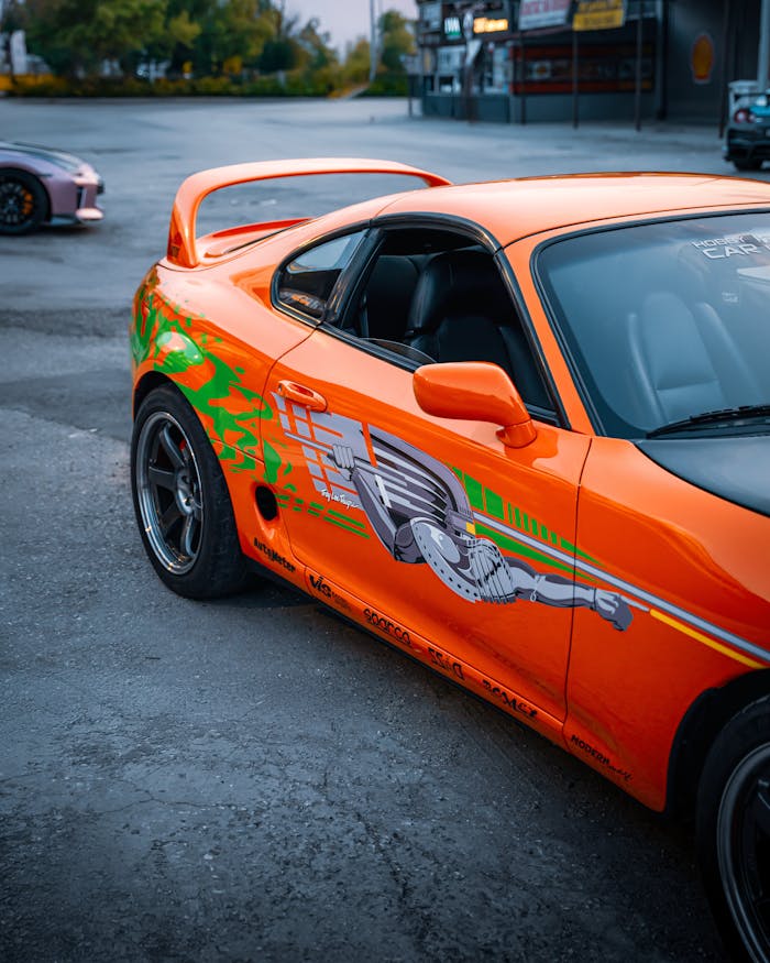 Bright orange Toyota Supra with custom graphics showcased in Ankara, Türkiye, exuding a sporty vibe.